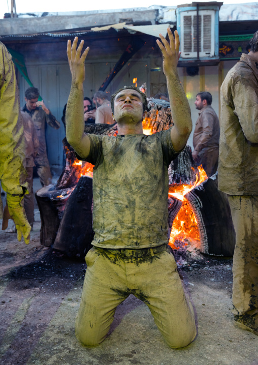 Iranian shiite muslim men pray and gather around a bonfire after rubbing mud on their bodies during the Kharrah Mali ritual to mark the Ashura day, Lorestan Province, Khorramabad, Iran