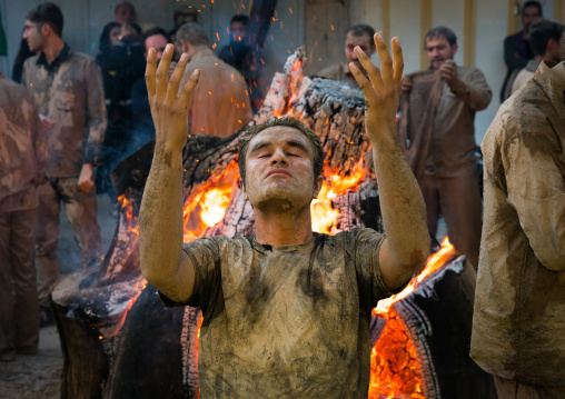 Iranian shiite muslim men pray and gather around a bonfire after rubbing mud on their bodies during the Kharrah Mali ritual to mark the Ashura day, Lorestan Province, Khorramabad, Iran