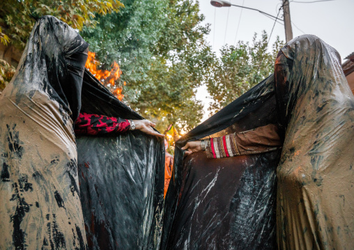 Iranian shiite muslim women gather around a bonfire after rubbing mud on their chadors during the Kharrah Mali ritual to mark the Ashura day, Lorestan Province, Khorramabad, Iran