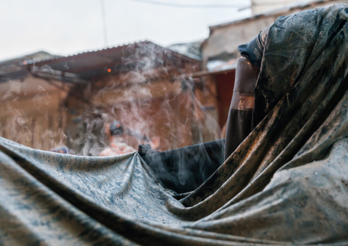 An Iranian shiite muslim woman stands in front of a bonfire after rubbing mud on her chador during the Kharrah Mali ritual to mark the Ashura day, Lorestan Province, Khorramabad, Iran