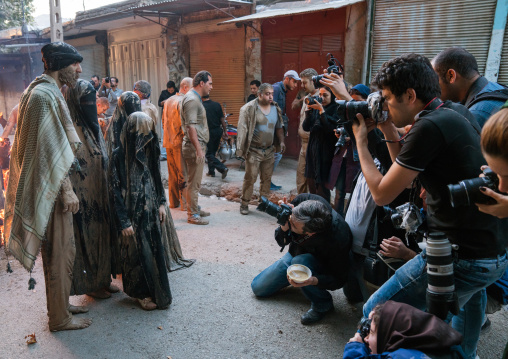 Photographers take pictures of iranian shiite muslims who gather around a bonfire after rubbing mud on their clothes during the Kharrah Mali ritual to mark the Ashura day, Lorestan Province, 