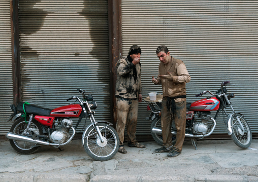 Two Iranian shiite muslim men eat their breakfasts after rubbing mud on their bodies early in the morning of Ashura day, Lorestan Province, Khorramabad, Iran