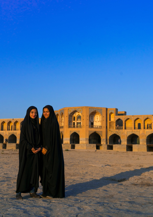 Portrait of two young women in chadors in front of Khaju bridge Pol-e Khaju, Isfahan Province, Isfahan, Iran