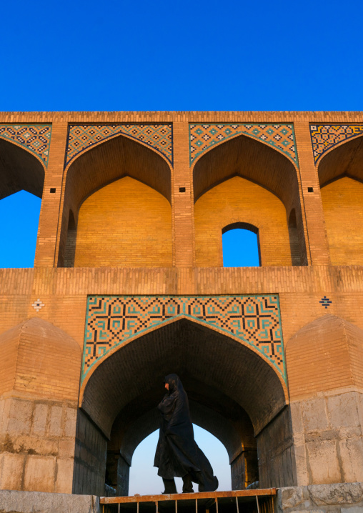 Veiled iranian woman passing in front of  Khaju bridge Pol-e Khaju, Isfahan Province, Isfahan, Iran