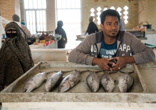 seller in the fish market with a woman wearing burqa, Qeshm Island, Salakh, Iran