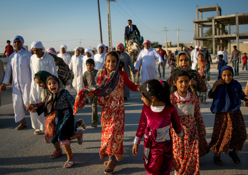 girls running in front of a groom riding his camel during the wedding ceremony, Qeshm Island, Salakh, Iran