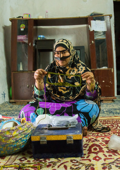 a bandari woman wearing a traditional mask called the burqa with a moustache shape, Qeshm Island, Salakh, Iran