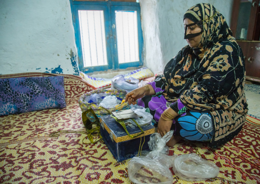 a bandari woman with a traditional mask called the burqa sewing, Qeshm Island, Salakh, Iran