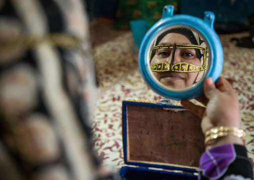 a bandari woman wearing a traditional mask looking herself in a mirror, Qeshm Island, Salakh, Iran