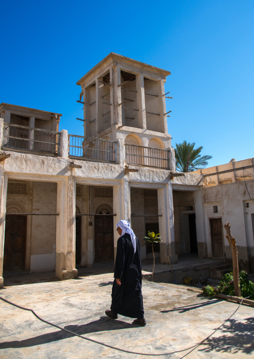 man passing in an old house courtyard with wind towers, Hormozgan, Bandar-e Kong, Iran