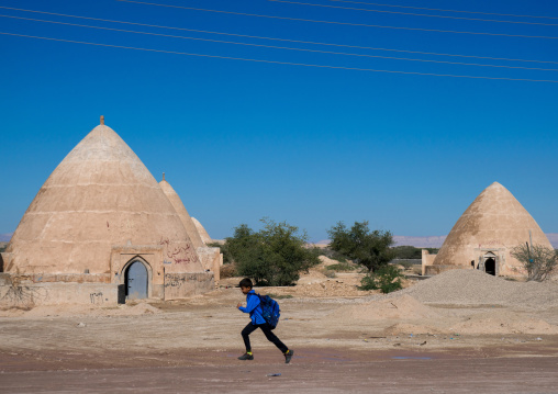 boy passing in front of water reservoirs, Hormozgan, Bandar-e Kong, Iran