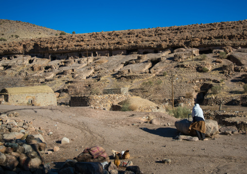 old widow woman collecting water at a well in the troglodyte village, Kerman province, Meymand, Iran