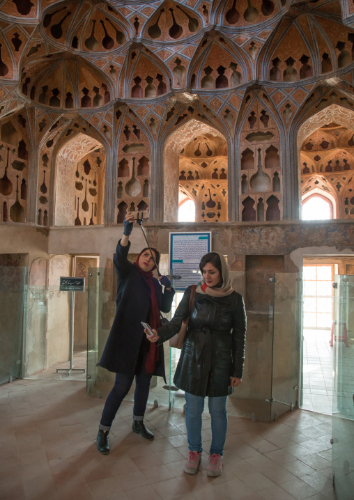 iranian women taking selfie picture in the acoustic ceiling in the music room of ali qapu palace, Isfahan Province, isfahan, Iran