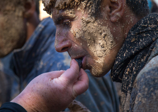 Iranian Shiite Muslim Woman Giving A Date Fruit To A Man Covered In Mud During Ashura Day, Kurdistan Province, Bijar, Iran