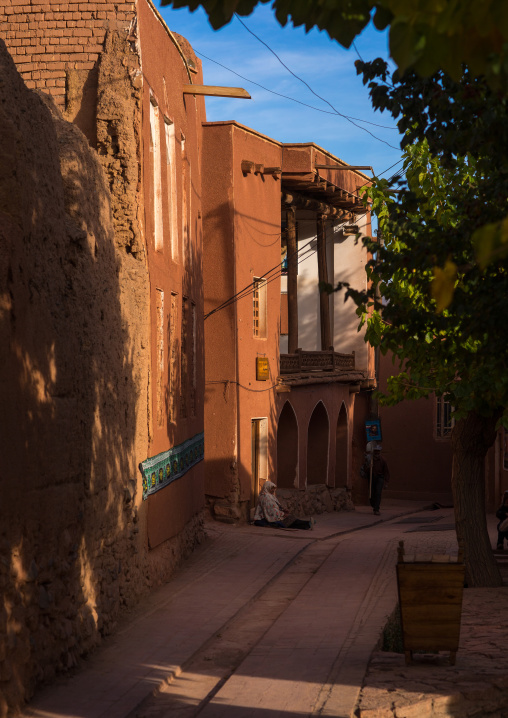 Sitting Woman Sitting In Front Of An Ancient Building With Ashura Decoration In Zoroastrian Village, Isfahan Province, Abyaneh, Iran