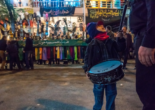 Boy With A Drum Speaking To His Father In Front Of An Alam On Ashura, The Day Of The Death Of Imam Hussein, Golestan Province, Gorgan, Iran