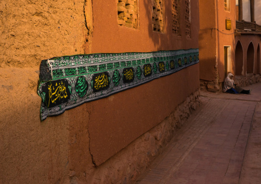 Sitting Woman Sitting In Front Of An Ancient Building With Ashura Decoration In Zoroastrian Village, Isfahan Province, Abyaneh, Iran