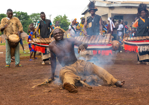 Shirtless man sitting in the fire during the Ngoro dance, Savanes district, Ndara, Ivory Coast