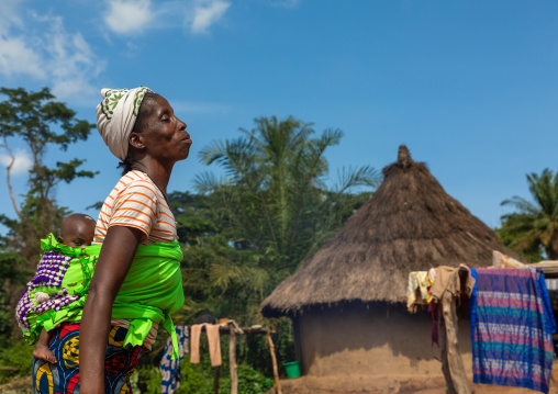 African mother carrying her child girl in her back, Bafing, Gboni, Ivory Coast