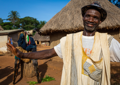 African man in front of the tall mask dance called Kwuya Gblen-Gbe in the Dan community, Bafing, Gboni, Ivory Coast