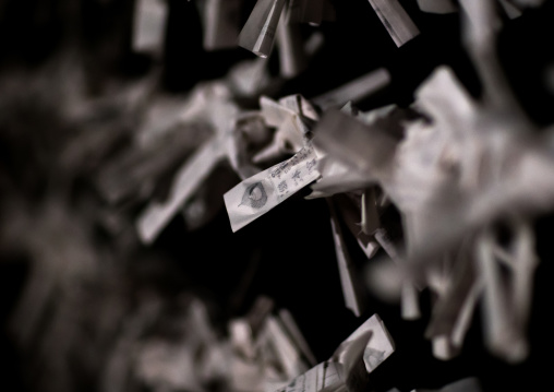 Folded paper fortunes tied to wires on a board at fushimi inari taisha shrine, Kansai region, Kyoto, Japan