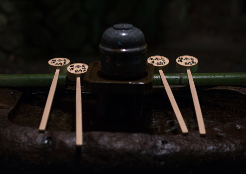 Drinking fountain in a japanese temple with bamboo cleansing cups in fushimi inari-taisha, Kansai region, Kyoto, Japan