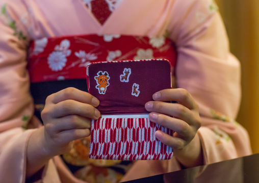 16 Years old maiko called chikasaya showing cartoon stickers in her purse, Kansai region, Kyoto, Japan