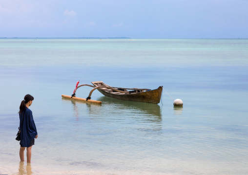 Japanses woman in front of a boat on the coastline, Yaeyama Islands, Taketomi island, Japan