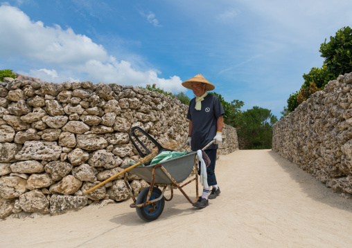 Gardener in a sandy alley in hoshinoya hotel, Yaeyama Islands, Taketomi island, Japan