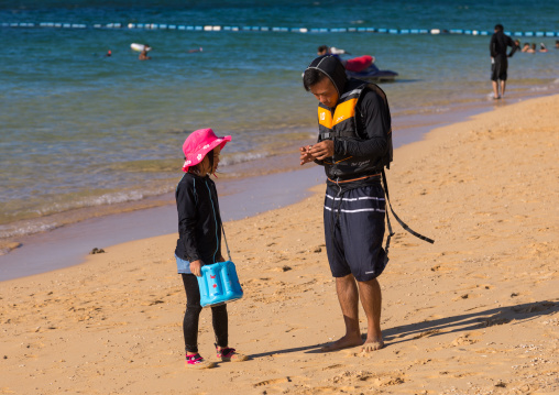 Japanese tourists with high protection against the sun in sunset beach, Yaeyama Islands, Ishigaki, Japan