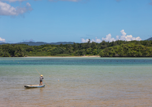 Japanese fisherman in tropical lagoon with clear blue water in Kabira bay, Yaeyama Islands, Ishigaki, Japan