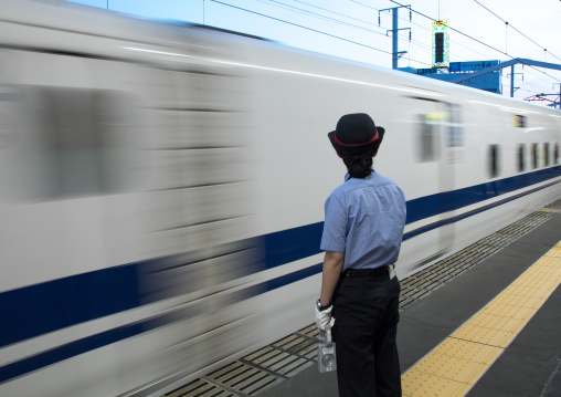 Japanese female station master in front of a Shinkansen train in a station, Hypgo Prefecture, Himeji, Japan