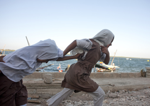 Two schoolgirl teenagers running alongside the dock, Lamu County, Lamu, Kenya