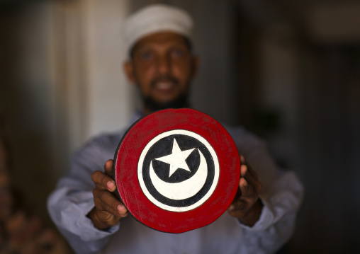 Wood carver holding crescent and star sign put on the dhows as lucky sign, Lamu County, Lamu, Kenya