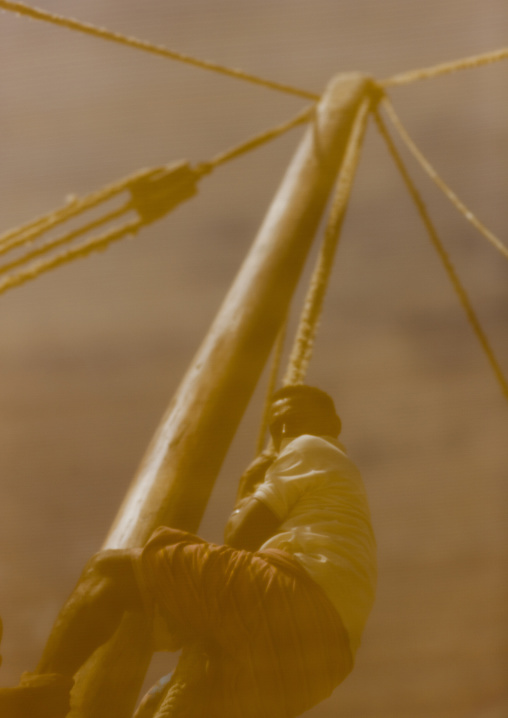 Man climbing along the mast on a dhow, Lamu County, Lamu, Kenya