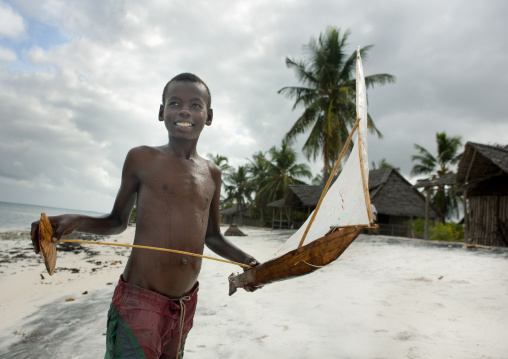 Young boy playing with a dhow boat model, Lamu County, Lamu, Kenya