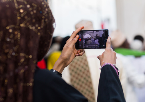 Sunni muslim woman taking pictures during the maulidi festivities in the street, Lamu county, Lamu town, Kenya