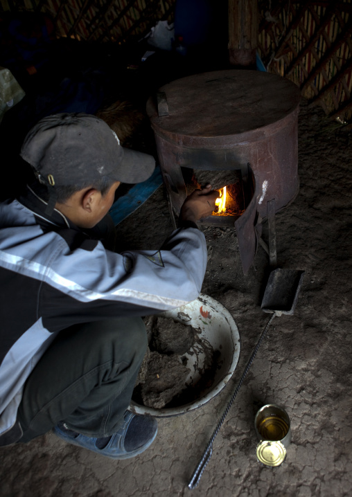 Boy With Cap Putting Dung In The Stove Of The Yurt, Saralasaz Jailoo, Kyrgyzstan