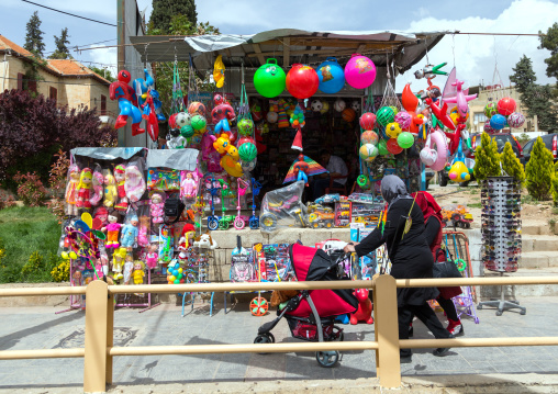 Lebanese woman with a baby-buggy
passing in front of a toy shop with her child, Beqaa Governorate, Baalbek, Lebanon