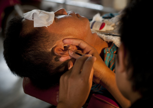 Hairdresser taking care of the ears, Pakse, Laos