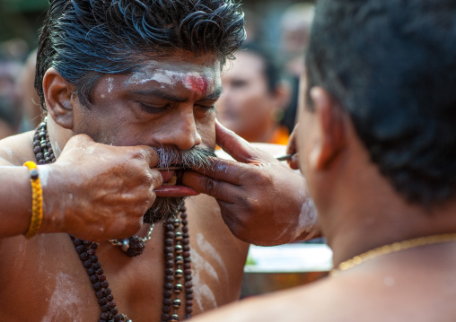 A Devotee Cheek Is Pierced With A Big Skewer By A Priest At Thaipusam Hindu Festival At Batu Caves, Southeast Asia, Kuala Lumpur, Malaysia