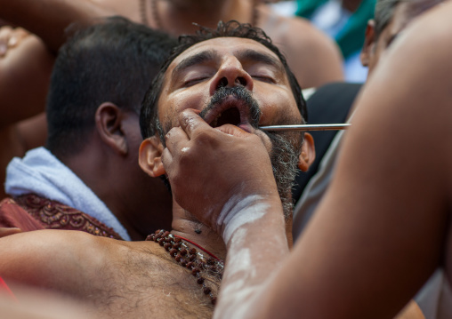 A Devotee Cheek Is Pierced With A Skewer By A Priest At Thaipusam Hindu Festival At Batu Caves, Southeast Asia, Kuala Lumpur, Malaysia