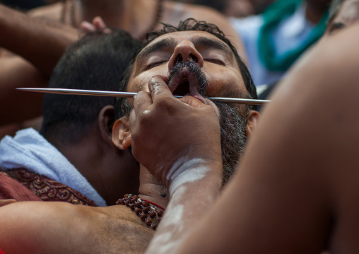 A Devotee Cheek Is Pierced With A Skewer By A Priest At Thaipusam Hindu Festival At Batu Caves, Southeast Asia, Kuala Lumpur, Malaysia