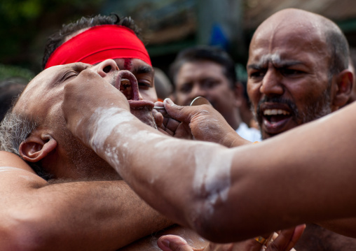 A Devotee Cheek Is Pierced With A Skewer By A Priest At Thaipusam Hindu Festival At Batu Caves, Southeast Asia, Kuala Lumpur, Malaysia