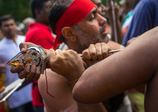 A Devotee Cheek Is Pierced With A Giant Skewer By A Priest At Thaipusam Hindu Festival At Batu Caves, Southeast Asia, Kuala Lumpur, Malaysia