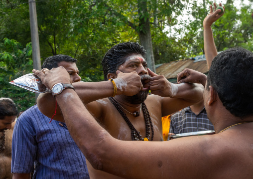 A Devotee Cheek Is Pierced With A Skewer By A Priest At Thaipusam Hindu Festival At Batu Caves, Southeast Asia, Kuala Lumpur, Malaysia