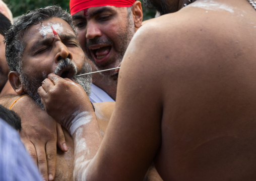 A Devotee Cheek Is Pierced With A Skewer By A Priest At Thaipusam Hindu Festival At Batu Caves, Southeast Asia, Kuala Lumpur, Malaysia