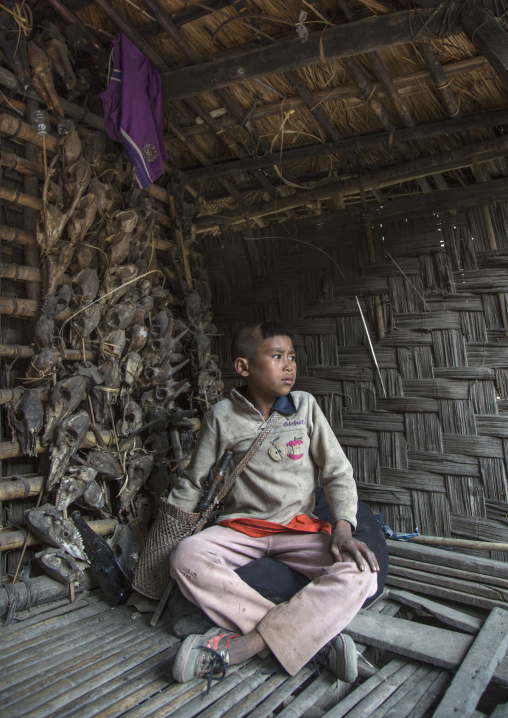 Chin Boy In Front Of Skulls At The Entrance Of His House, Mindat, Myanmar