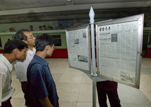 North Korean people reading the offical state newspaper in a subway station, Pyongan Province, Pyongyang, North Korea