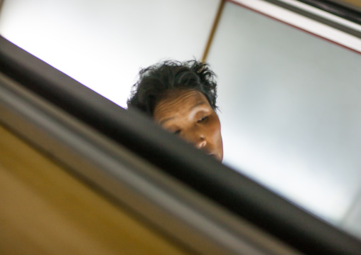 Tired North Korean woman resting on escalators stairs inside subway station, Pyongan Province, Pyongyang, North Korea